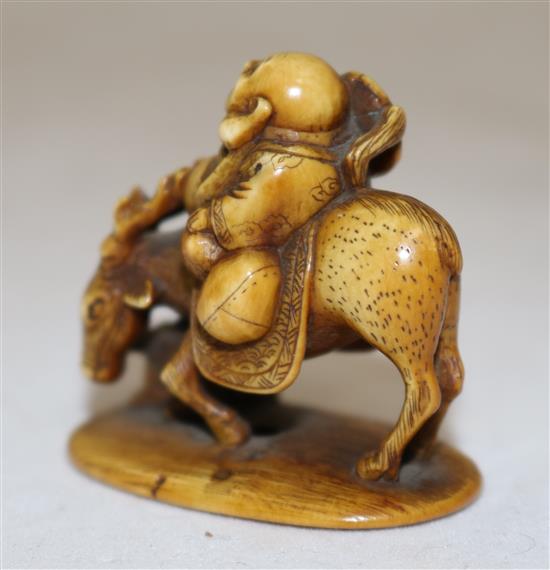 A Japanese stained ivory okimono netsuke of Hotei riding a deer, signed Tomochika, Meiji period, 4.1cm